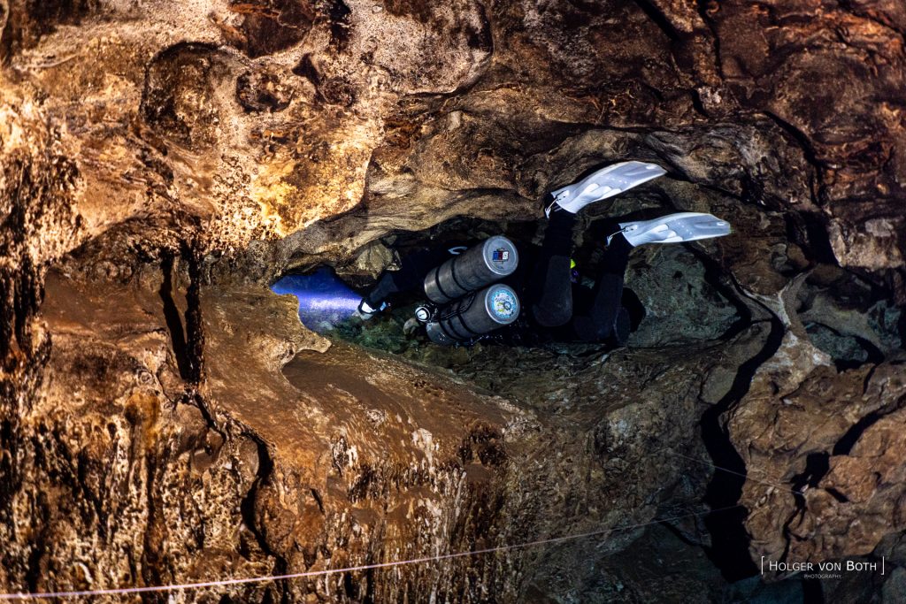 Sidemount cave diver passing a tight underwater restriction inside Mitoho Cave, Madagascar.